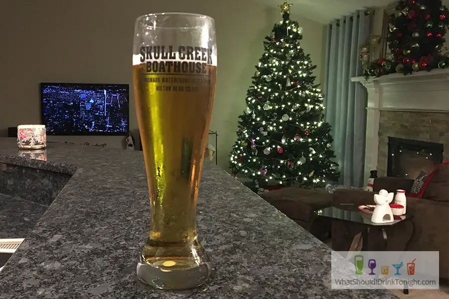 tall pilsner glass with frozen beer in front of a tv and christmas tree
